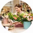 Responsable de atención al cliente revisando un ramo fresco junto al mostrador de la floristería