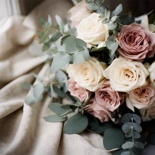 Detalle de rosas de jardín y eucalipto en un ramo de novia sobre tela de lino